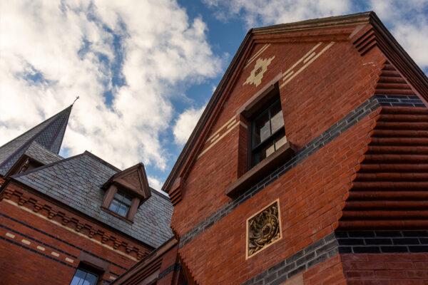 Brick facade of Sage Hall with the blue sky visible above.