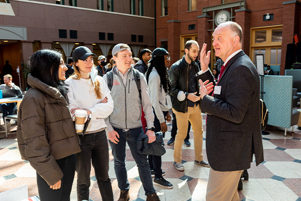 Dean Andrew Karolyi Speaks with students in the Sage Hall atrium.